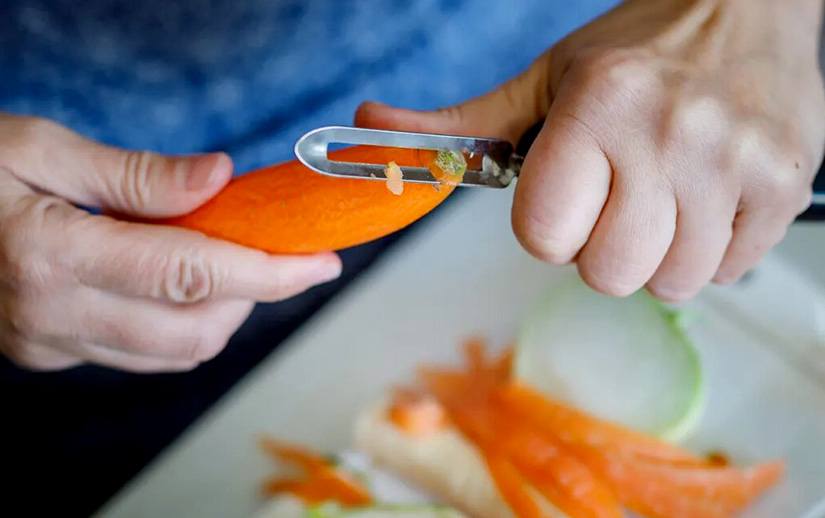 A man peeling carrots with a peeler