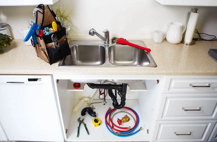 A kitchen sink with tools underneath, illustrating how to replace kitchen faucet effectively